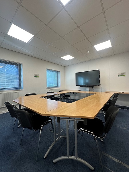Eight chairs around a table and an interactive screen in the large meeting room at Maylands Business Centre