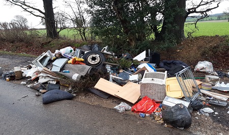 Example of fly-tipping Large pile of waste including tyres, bin bags and furniture dumped at the edge of a country lane