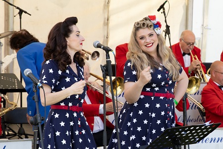 Two singers from the Polka Dot Dolls wearing blue an white 1940s style dresses on stage at the Armed Forces Day event
