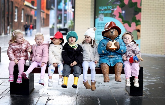 Children sitting on special bench with model of Paddington